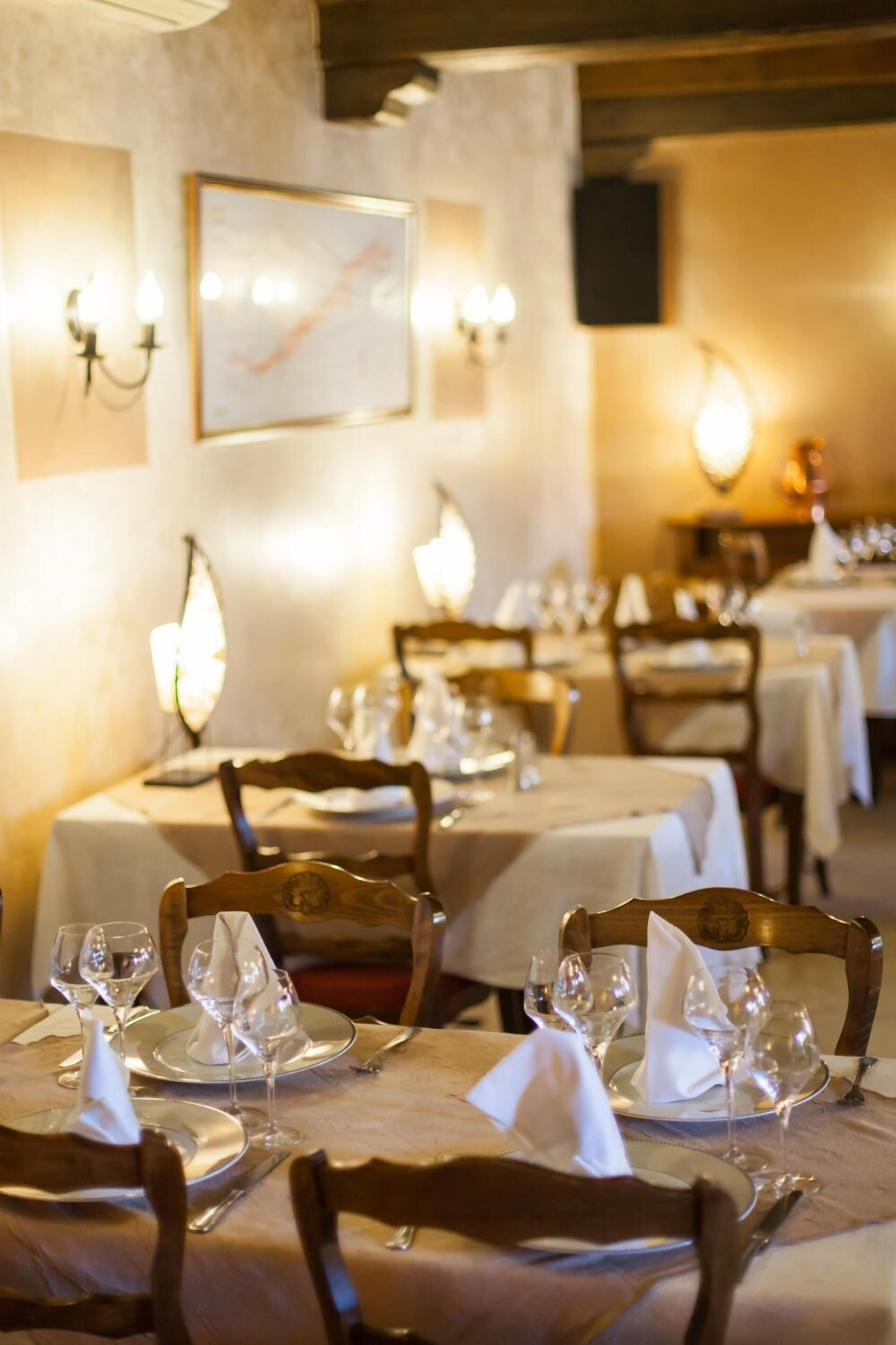 En restaurant med borde dækket til spisning, hvide duge og pænt anrettet bestik.