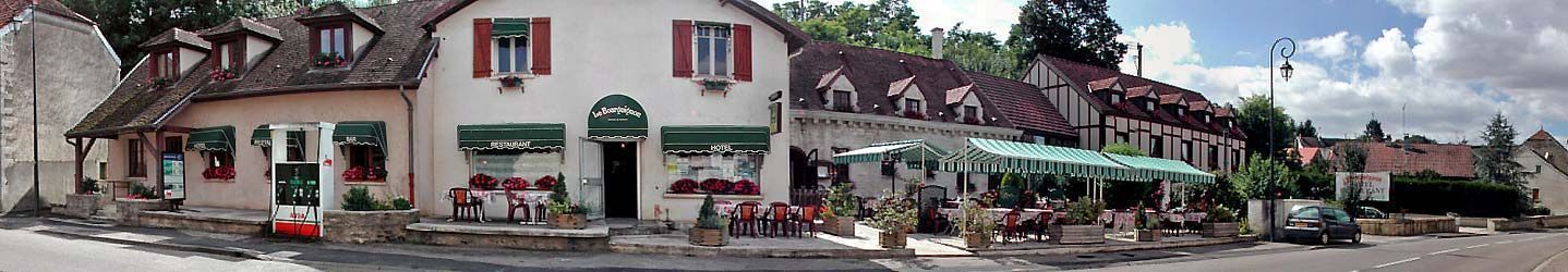A traditional European building with a restaurant on the ground floor, outdoor seating, and a visible gas station.