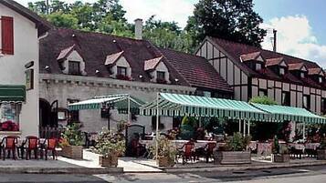 A traditional European building with a restaurant on the ground floor, outdoor seating, and a visible gas station.
