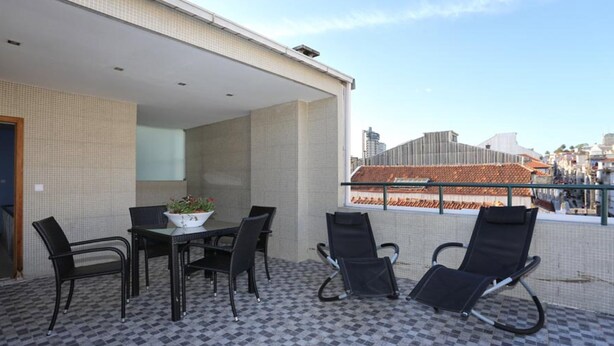 An outdoor seating area with a table and chairs, a potted plant, and a view of buildings in the background. - Oporto City Center Apartments (Porto)