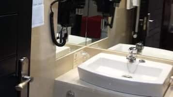 A bathroom with a white sink, a mirror, and a telephone.