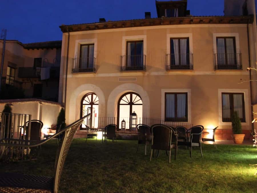 A two-story building with a balcony, outdoor seating, and a well-maintained lawn.