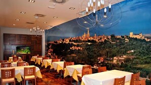 A restaurant with tables set for dining, a television on the wall, and a mural of a cityscape.