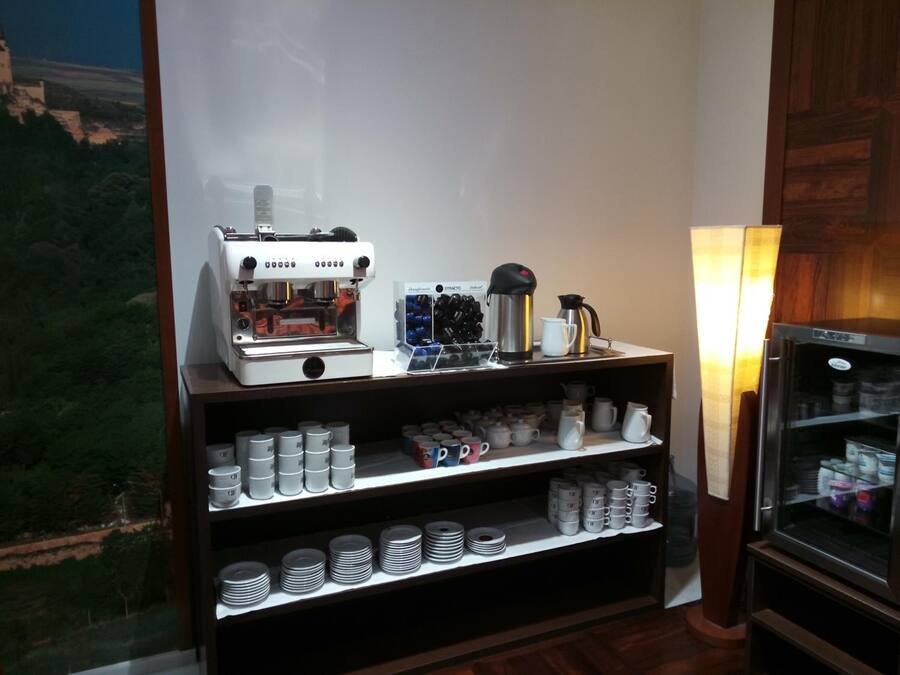 Una estación de café con una cafetera, tazas y un refrigerador.