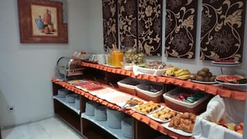 A buffet setup with various food items and beverages, including fruits, pastries, and condiments.