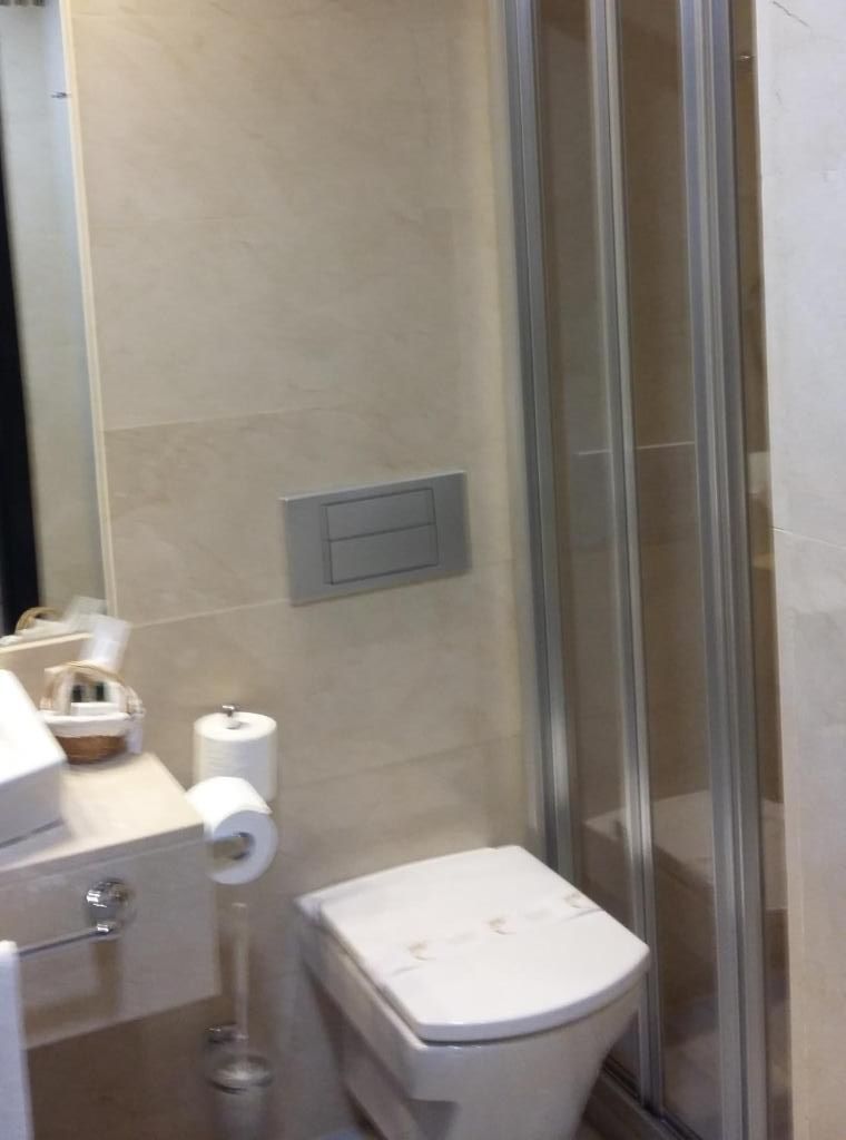 Un baño con inodoro, cabina de ducha de vidrio y perchero.
