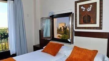 A hotel room with a bed, a window with a view, a painting on the wall, and a nightstand.