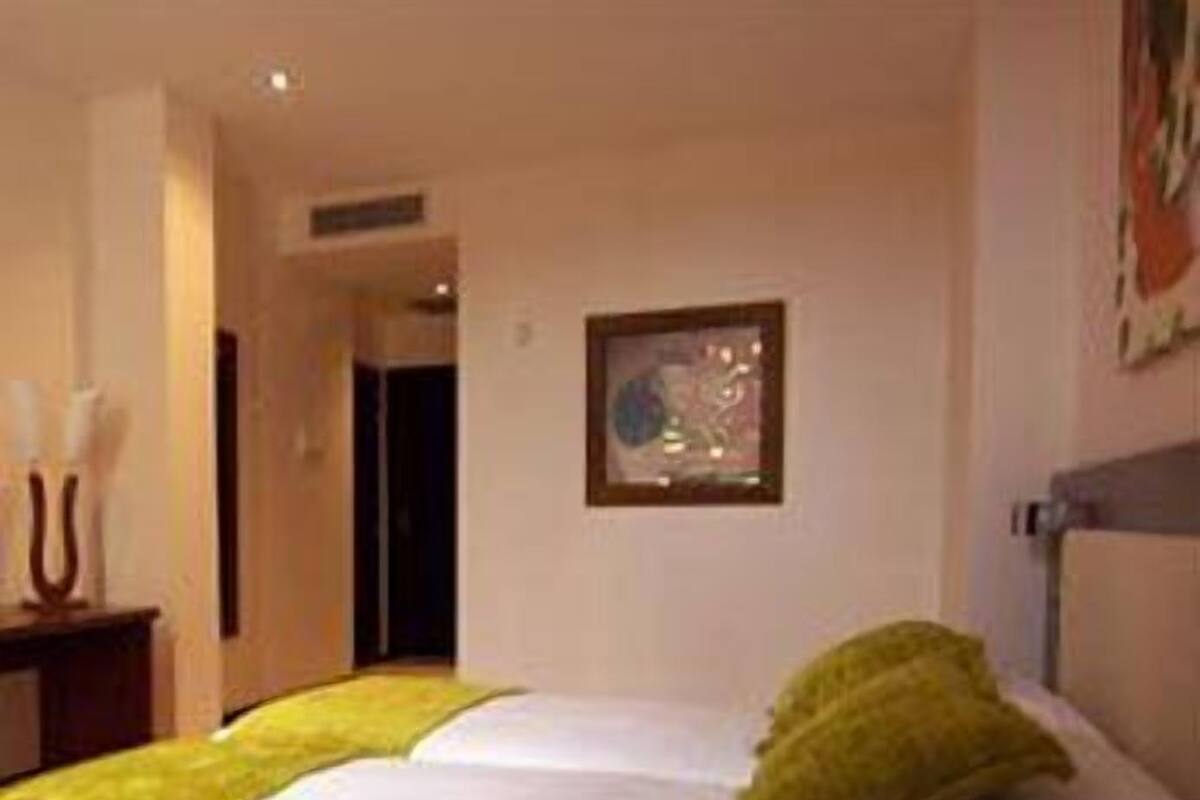 Una habitación de hotel con cama, una mesita de noche y un cuadro en la pared.