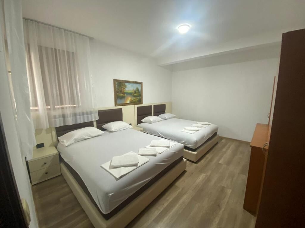 A hotel room with two beds, a painting on the wall, and a wooden floor.