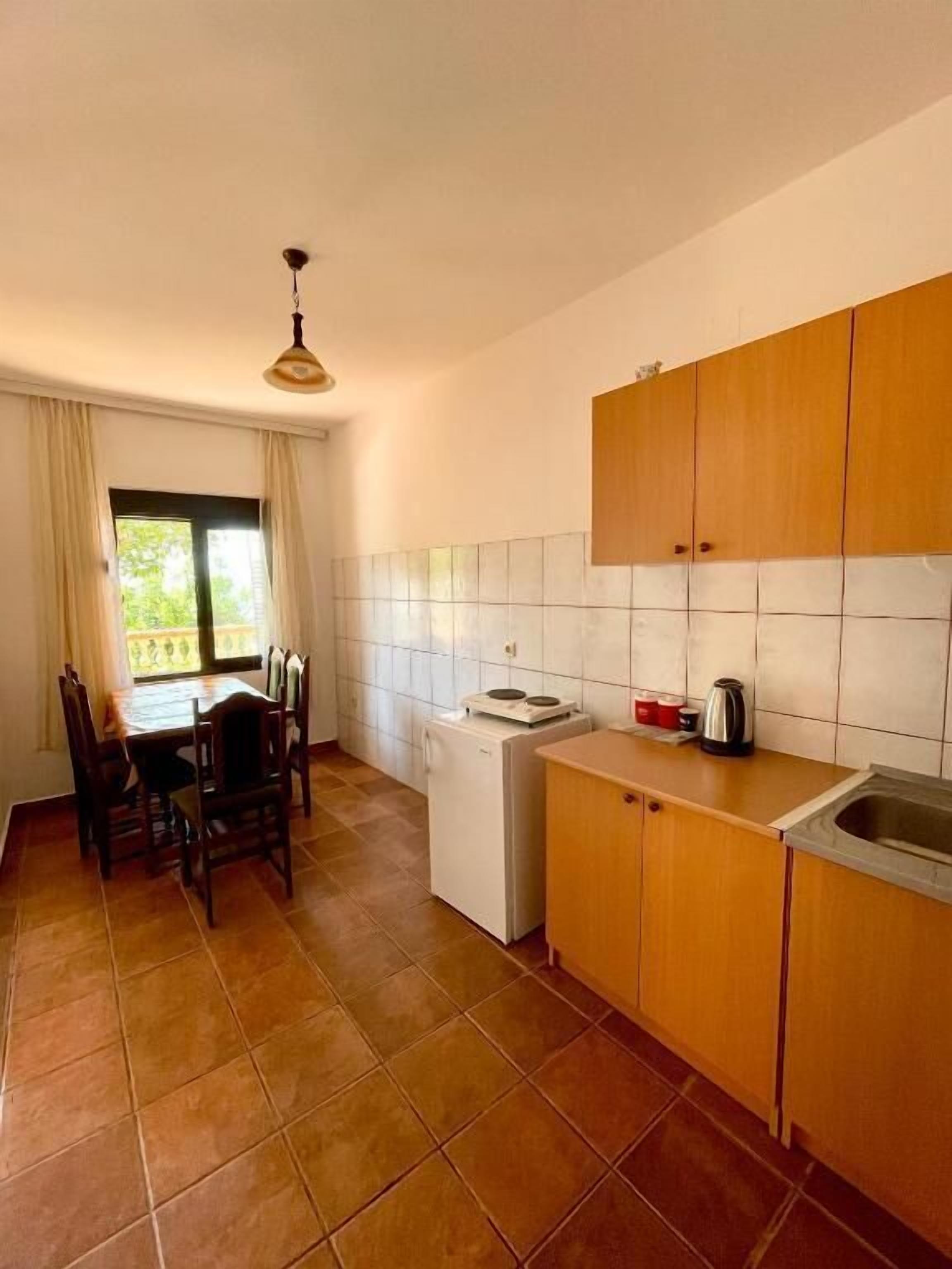A kitchen with wooden cabinets, a white refrigerator, a sink, and a dining area with chairs and a table.