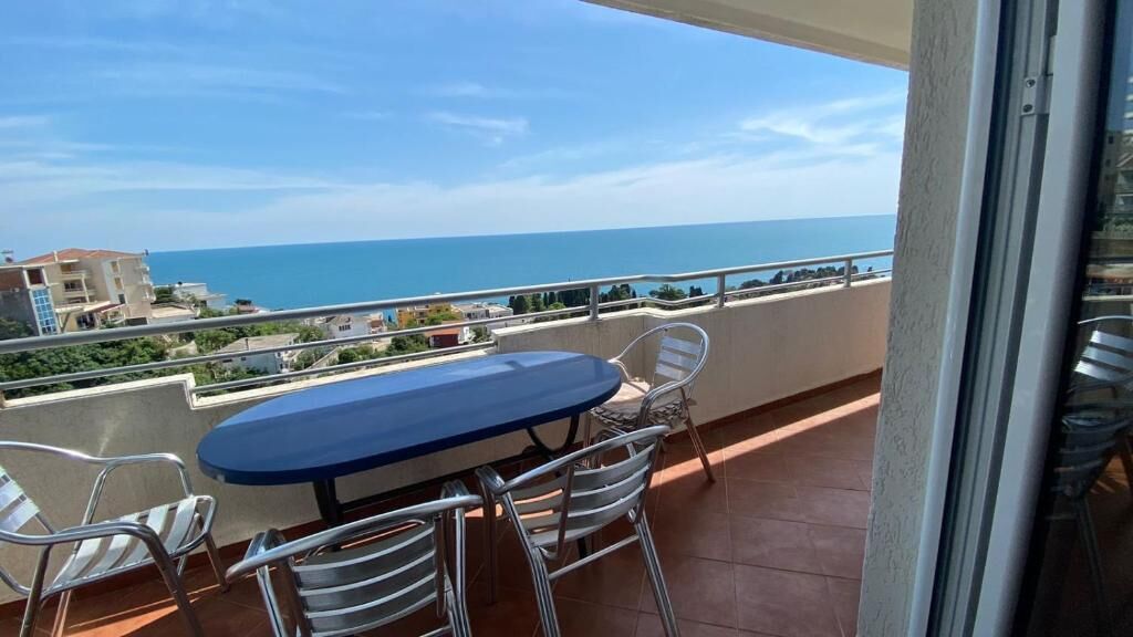 Un balcon avec une table et des chaises, offrant une vue sur la côte.
