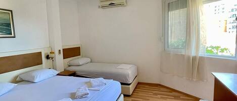 Une chambre d’hôtel avec un grand lit, un plus petit lit, un bureau et une fenêtre avec des rideaux.
