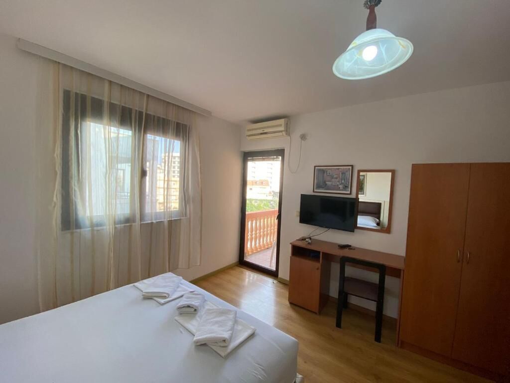 A hotel room with a bed, a desk, a television, and a wardrobe.