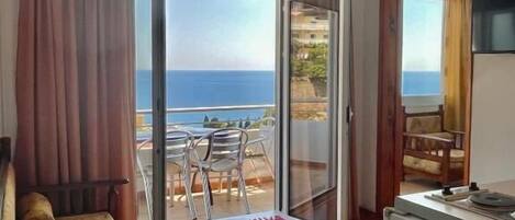 Un salón con un sofá, una mesa y vista al mar a través de un ventanal.