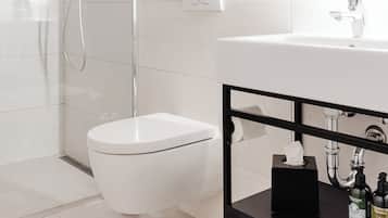 A modern bathroom with a glass-enclosed shower, a white toilet, and a black vanity with toiletries.