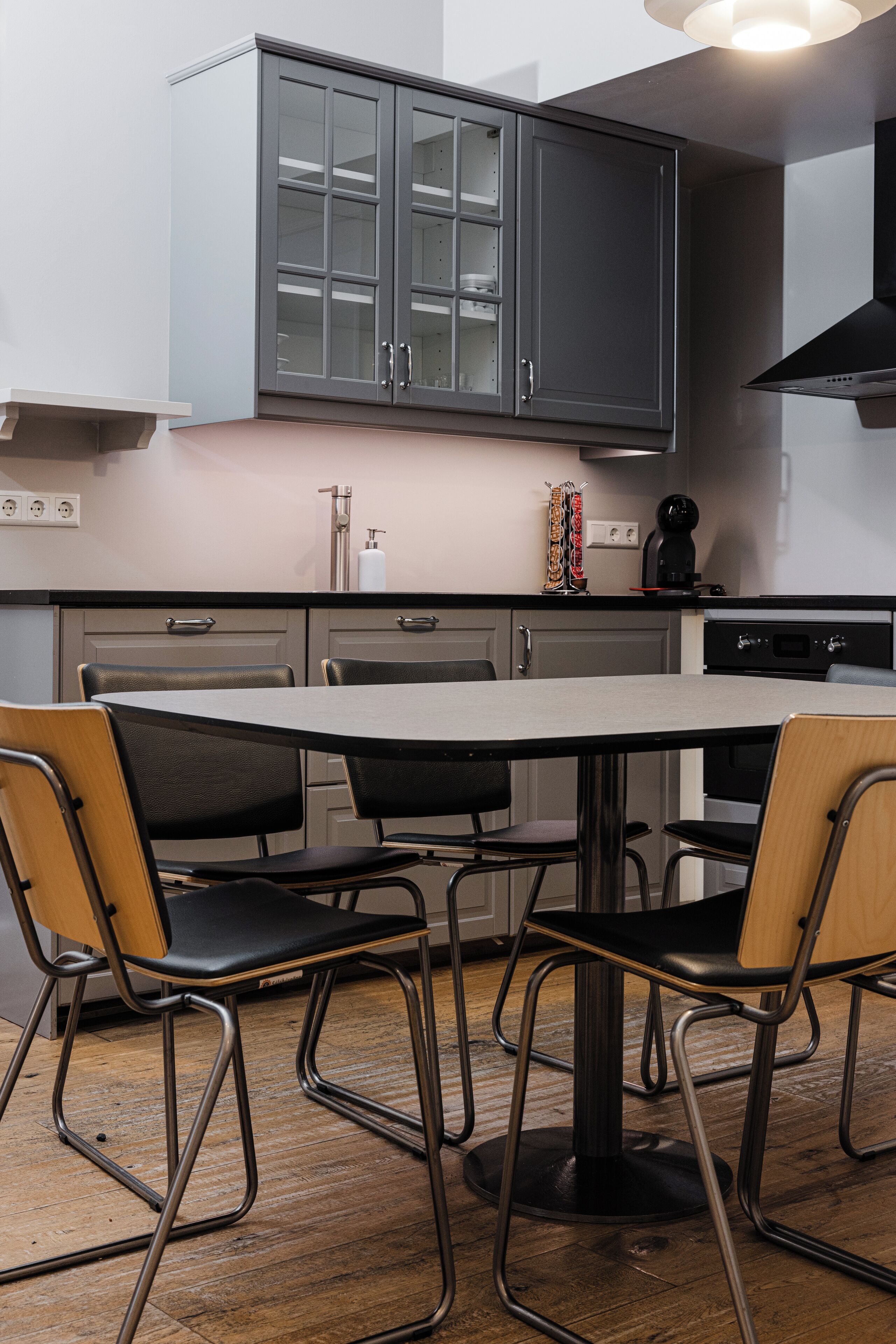 Une cuisine moderne avec une table ronde et quatre chaises, un four encastré et une hotte aspirante.
