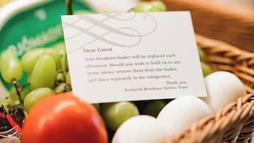 A breakfast basket with a note, containing grapes, tomatoes, and eggs.