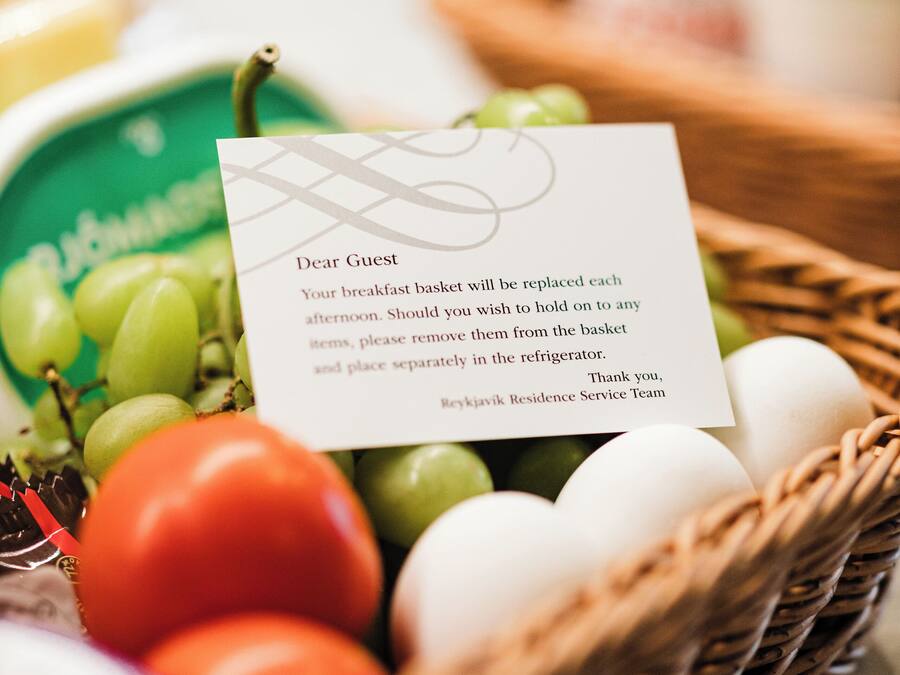A breakfast basket with a note, containing grapes, tomatoes, and eggs.