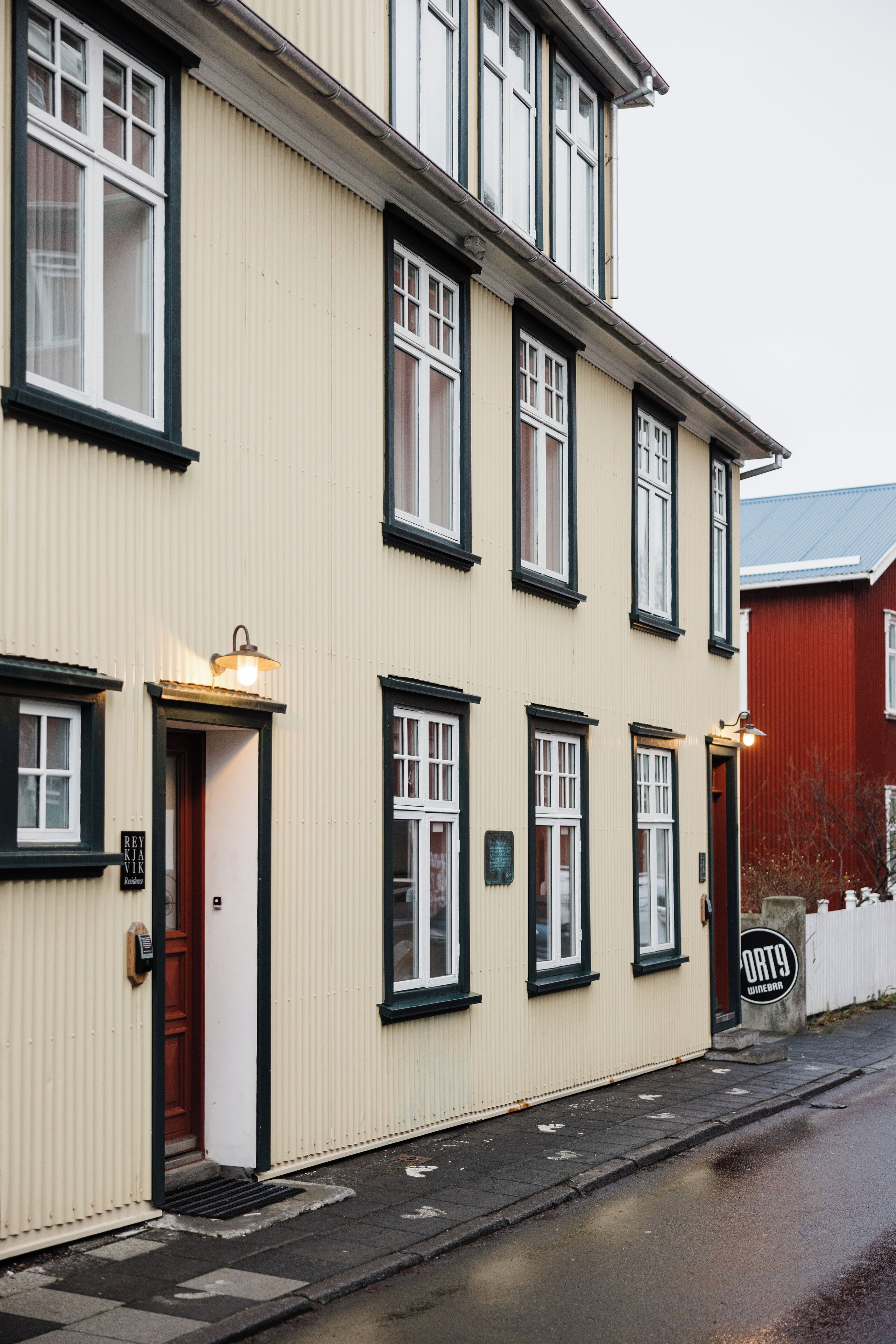 A cream-colored building with black-framed windows and a red door.