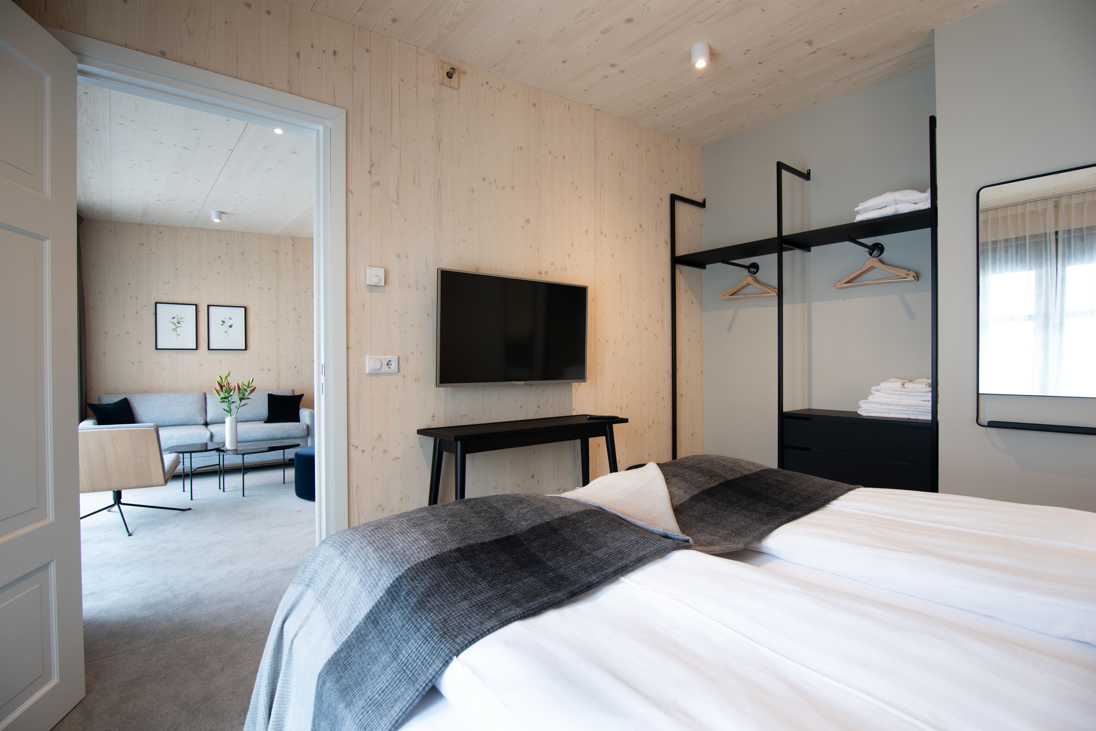 Ett modernt hotellrum med en stor säng, en platt-TV, ett skrivbord och en sittgrupp med en soffa och fåtöljer.