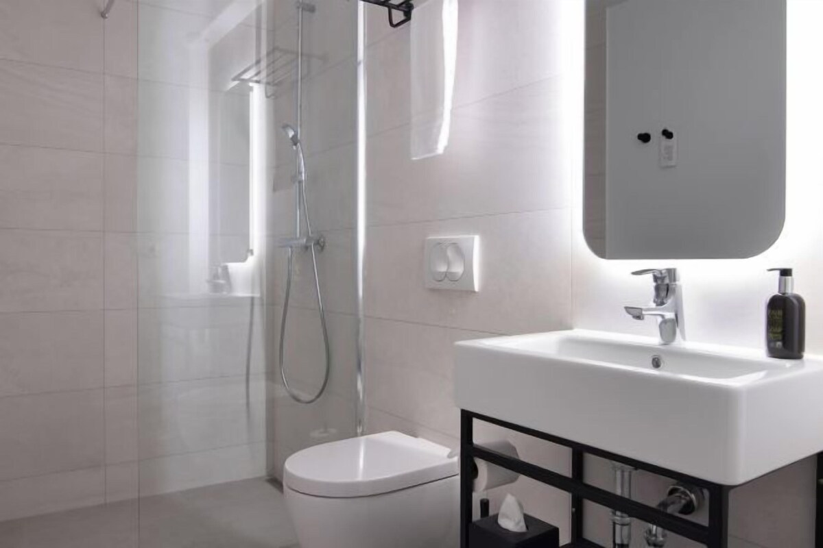 A modern bathroom with a shower, toilet, and sink.