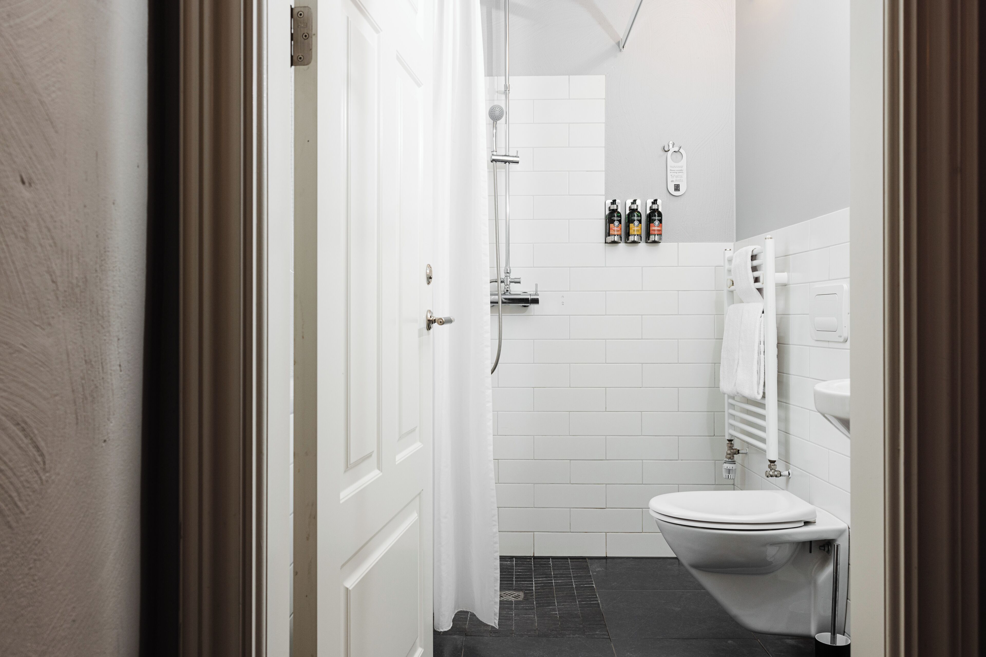 A bathroom with a white toilet, a shower, and a towel rack.