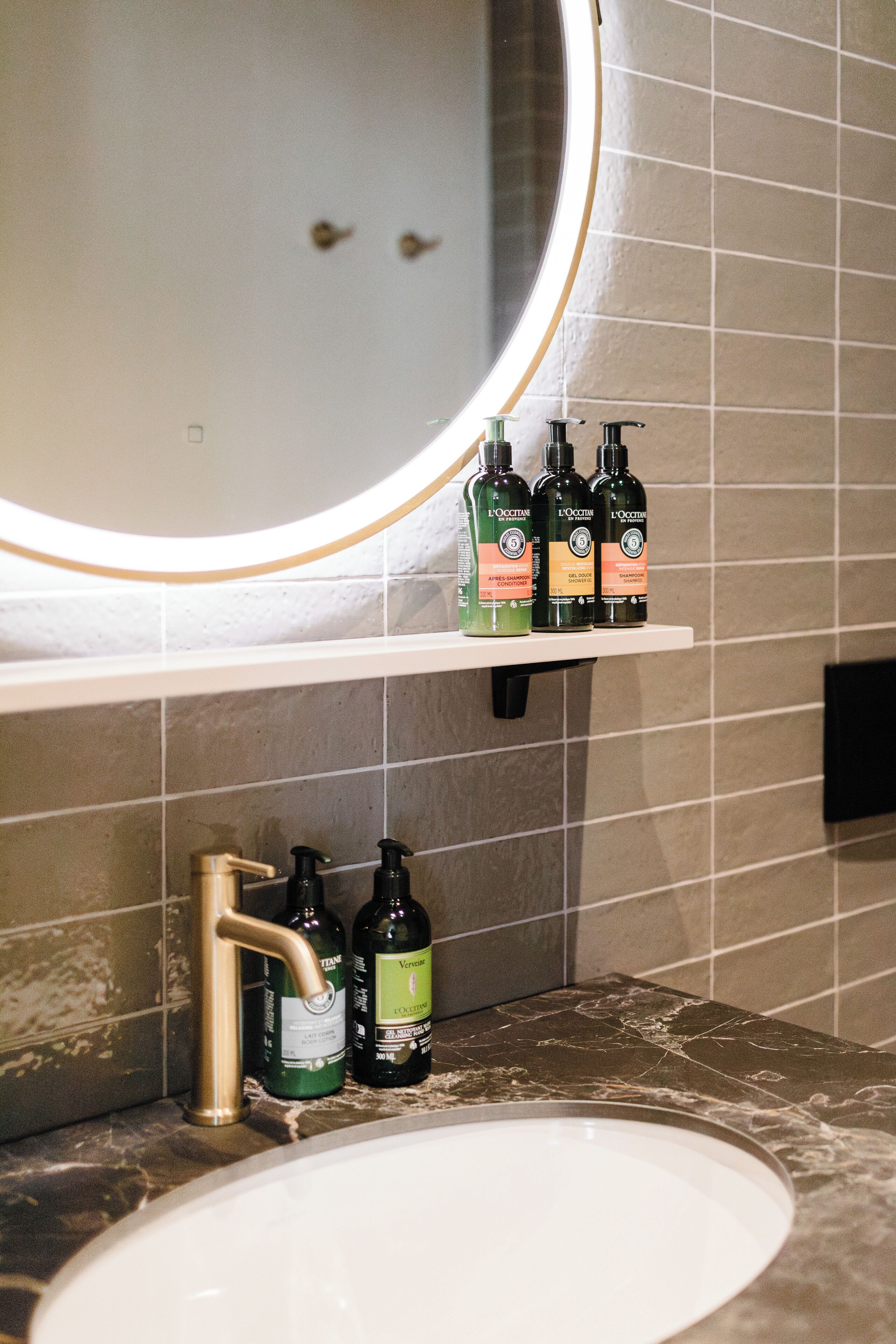A bathroom with a sink, mirror, and shelves holding toiletries.