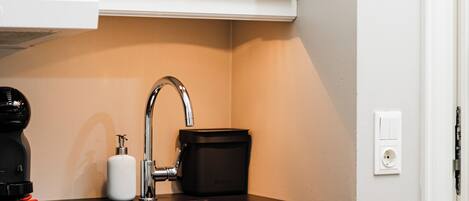 A kitchen with white cabinets, a black countertop, a sink, and a coffee maker.