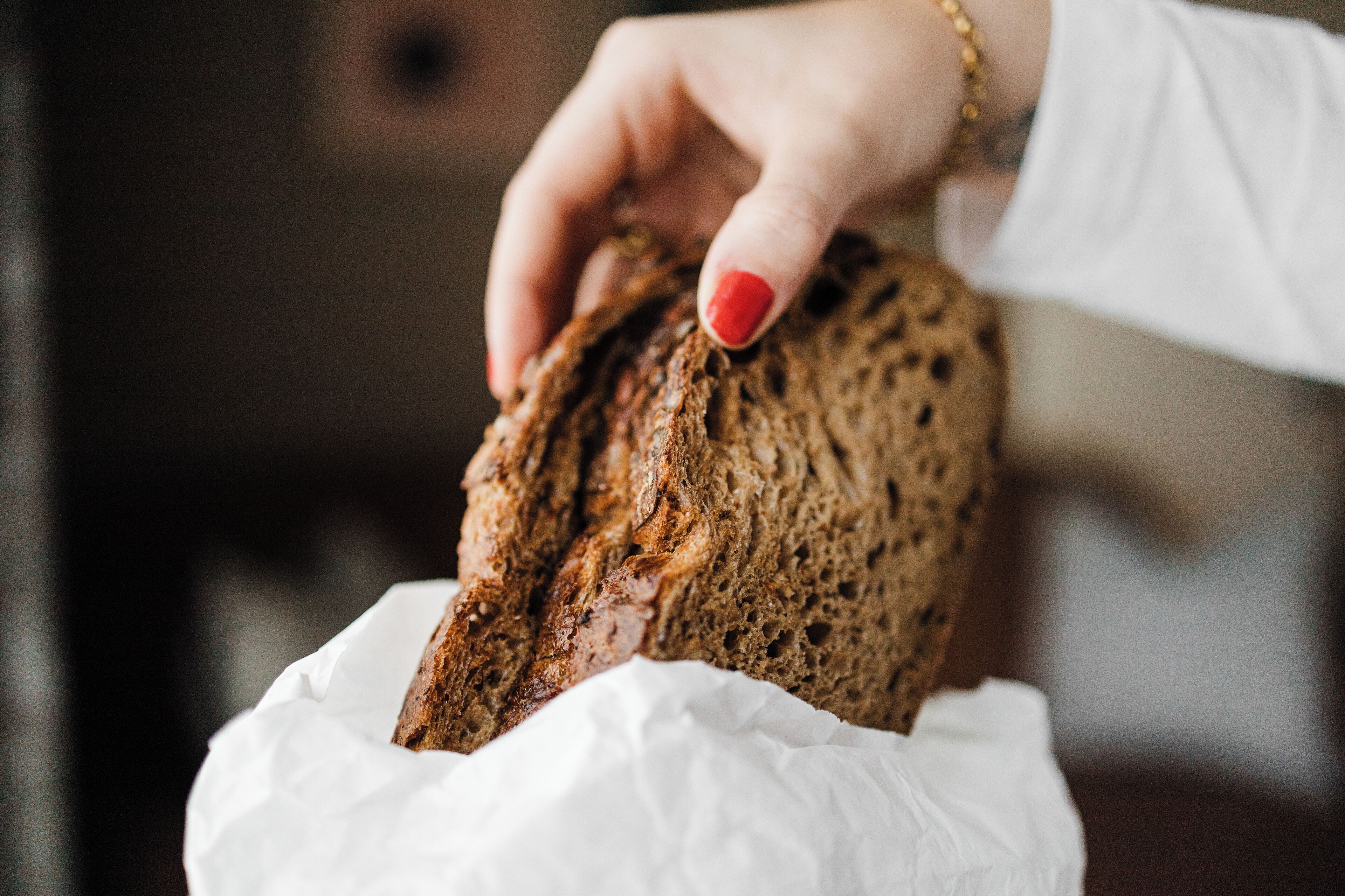 Une main tenant une miche de pain au-dessus d’une feuille de papier blanche.