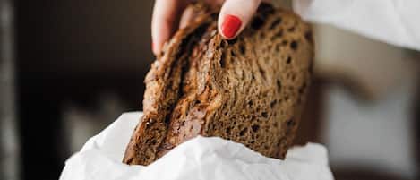 Une main tenant une miche de pain au-dessus d’une feuille de papier blanche.