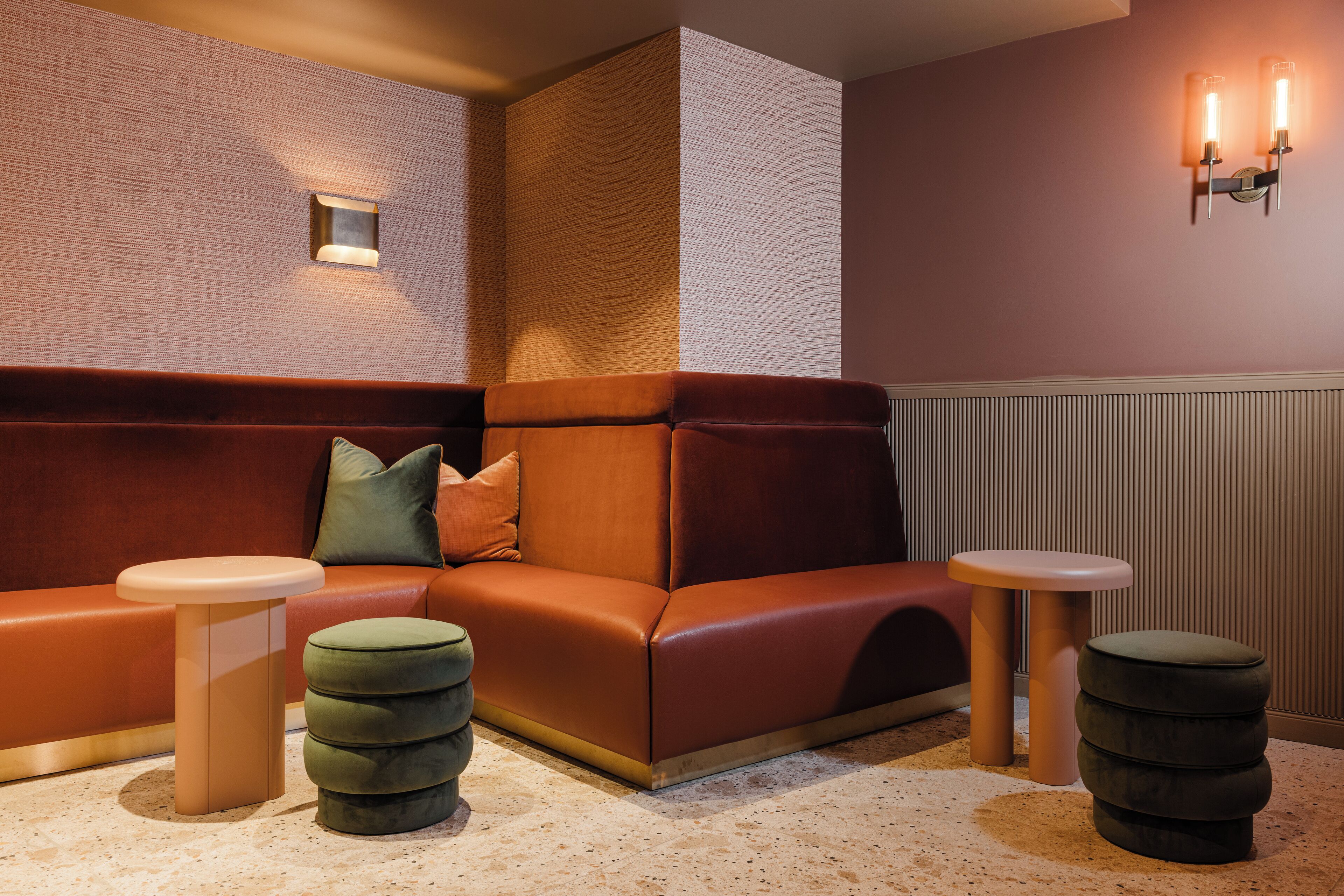 Un coin salon avec un canapé confortable, deux petites tables d’appoint rondes et un petit tabouret.