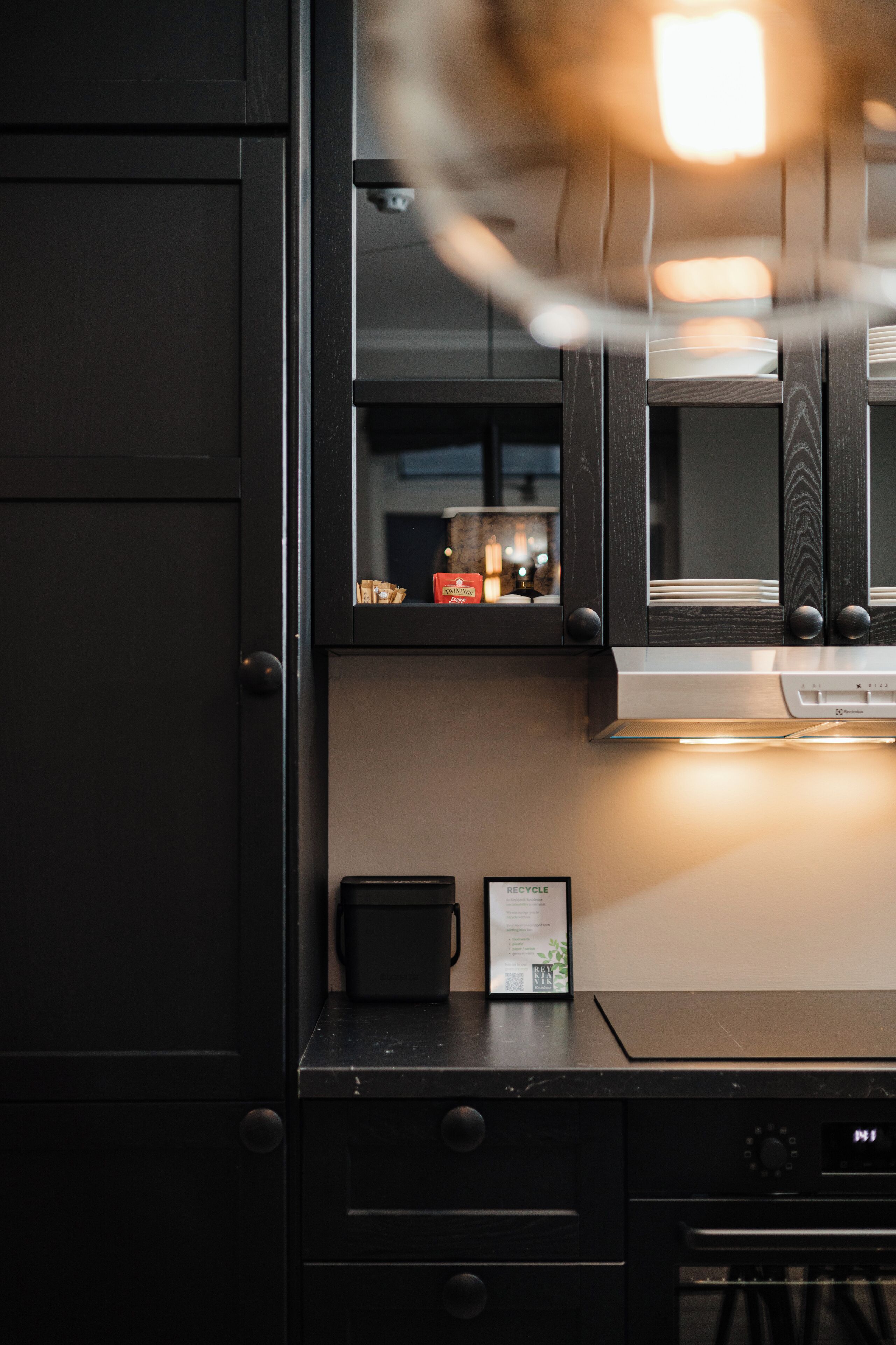 A kitchen with dark cabinetry, a countertop, and a digital clock.