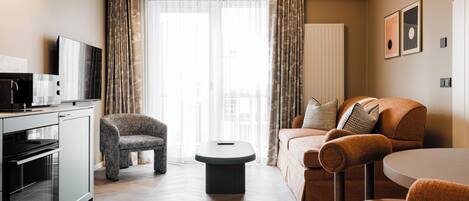 Ein modernes Wohnzimmer mit einer Couch, einem Sessel, einem Couchtisch und einem Fernseher.