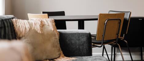 Una sala de estar moderna con un sofá, una mesa de comedor y sillas. En la pared, se observan impresiones enmarcadas de motivos botánicos.