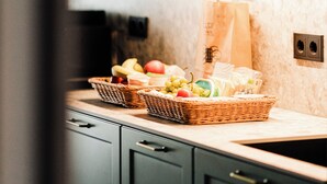 A kitchen with dark cabinets, a countertop with a basket of fruits, and a paper bag.