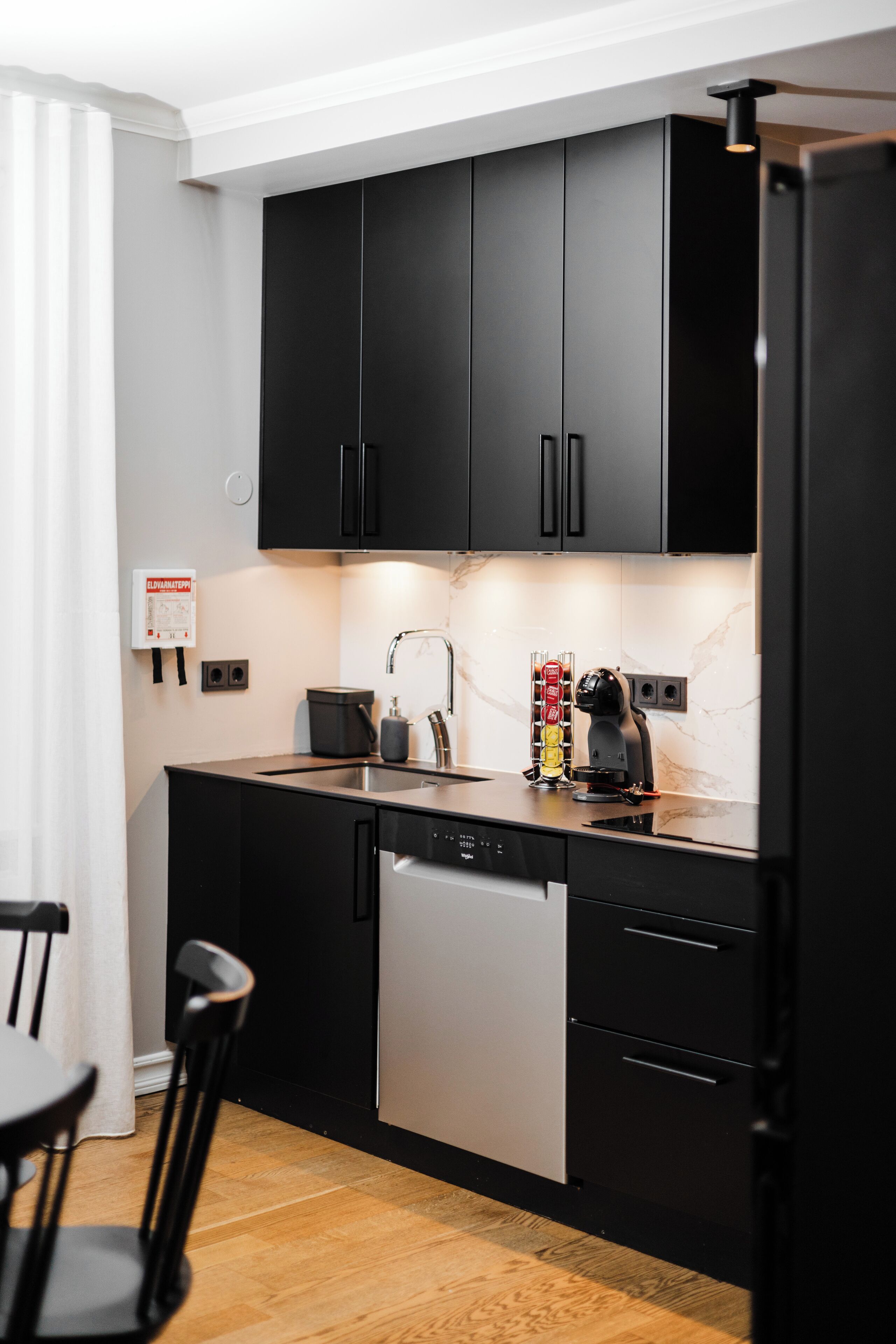 Una cocina moderna con armarios negros, lavavajillas y cafetera.