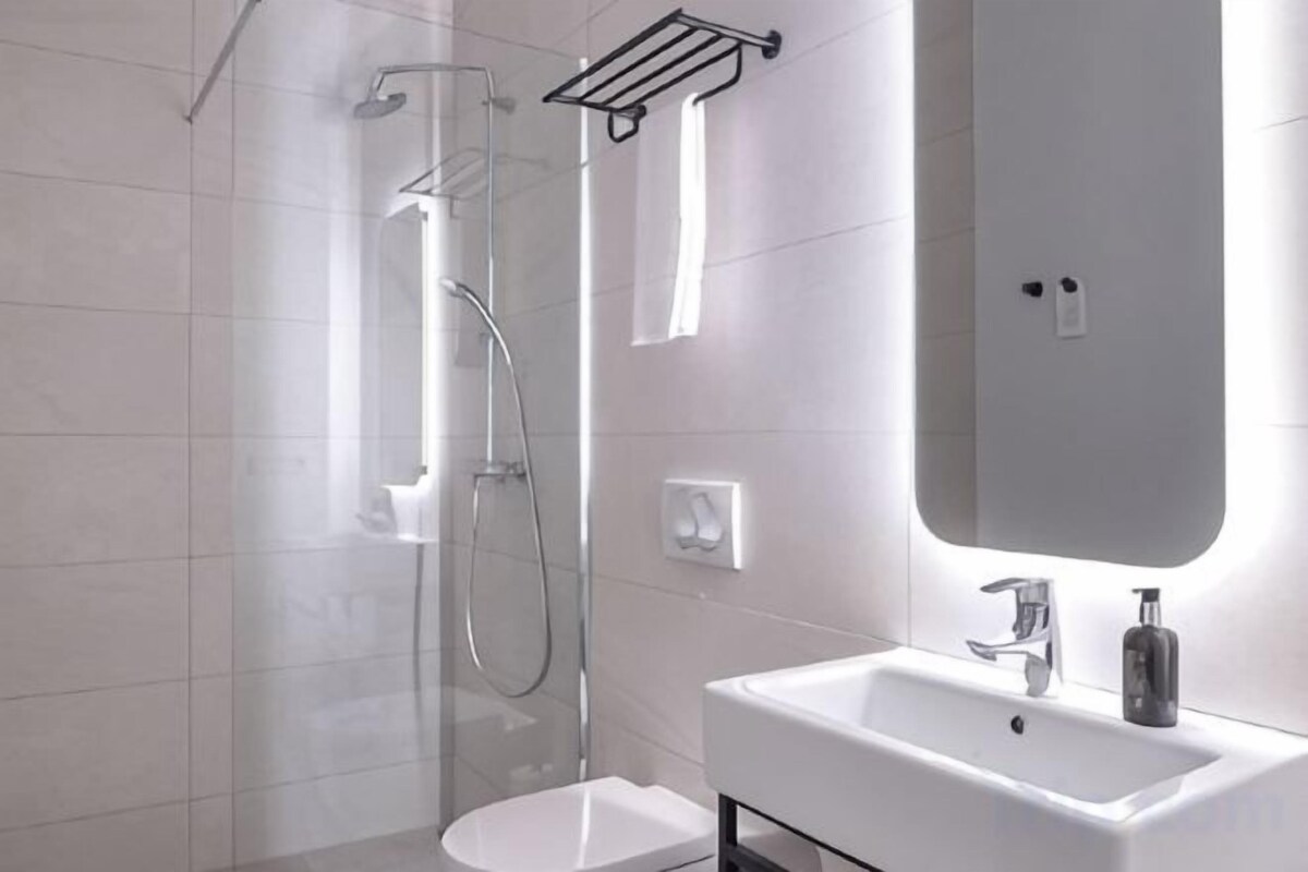 Une salle de bain moderne avec une douche à parois de verre, un lavabo blanc et un miroir.