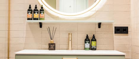 A bathroom with a round mirror, a white countertop, and various toiletries.