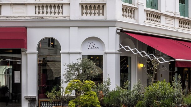 A building with a classic architectural style, featuring arched windows and a red awning.