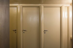 Conjunto de três portas bege com puxadores, provavelmente dando acesso a quartos privativos.