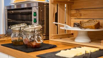 Un plan de travail de cuisine avec un pain de mie posé sur un présentoir à gâteaux blanc, un four en acier inoxydable et deux bocaux en verre avec leurs couvercles.
