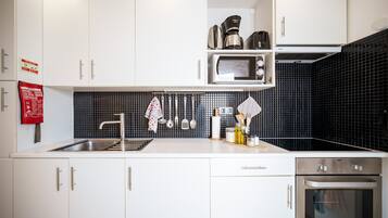 A modern kitchen with white cabinets, a stainless steel sink, a microwave, and an oven.