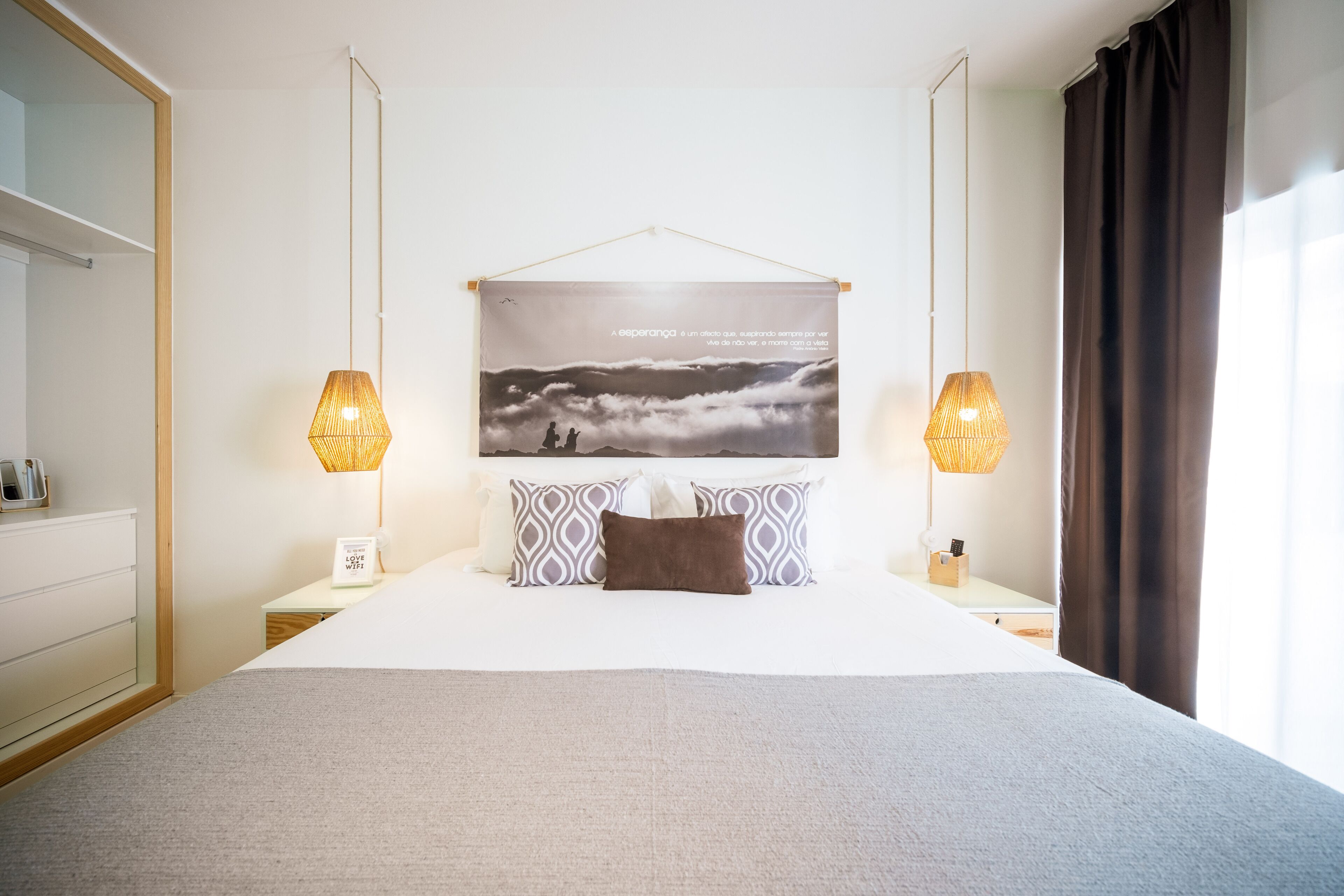 Une chambre d’hôtel avec un grand lit, deux lampes de chevet, une œuvre d’art accrochée au mur et une vue sur l’extérieur.