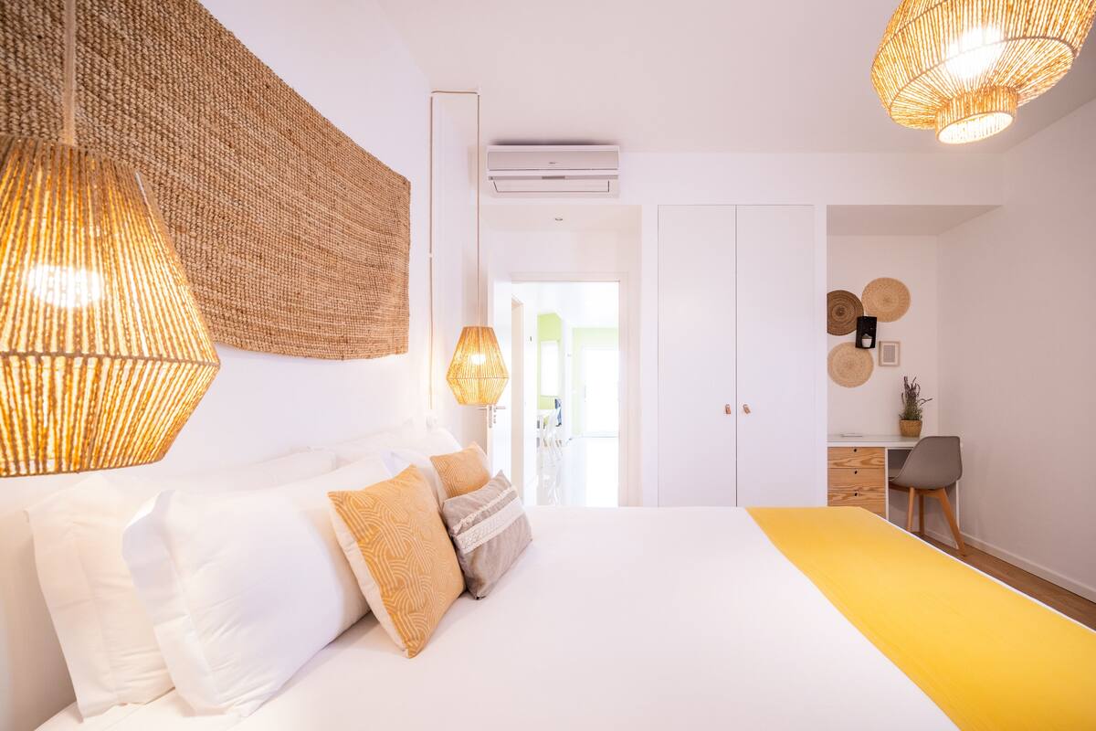 Een moderne slaapkamer met een groot bed, twee bedlampen en een bureau met stoel.