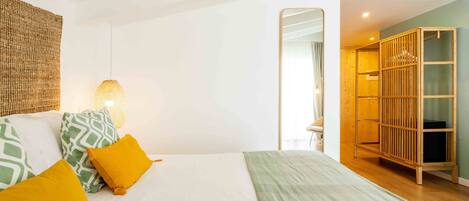 Un dormitorio con cama, almohadas, una lámpara colgante y un armario de madera.