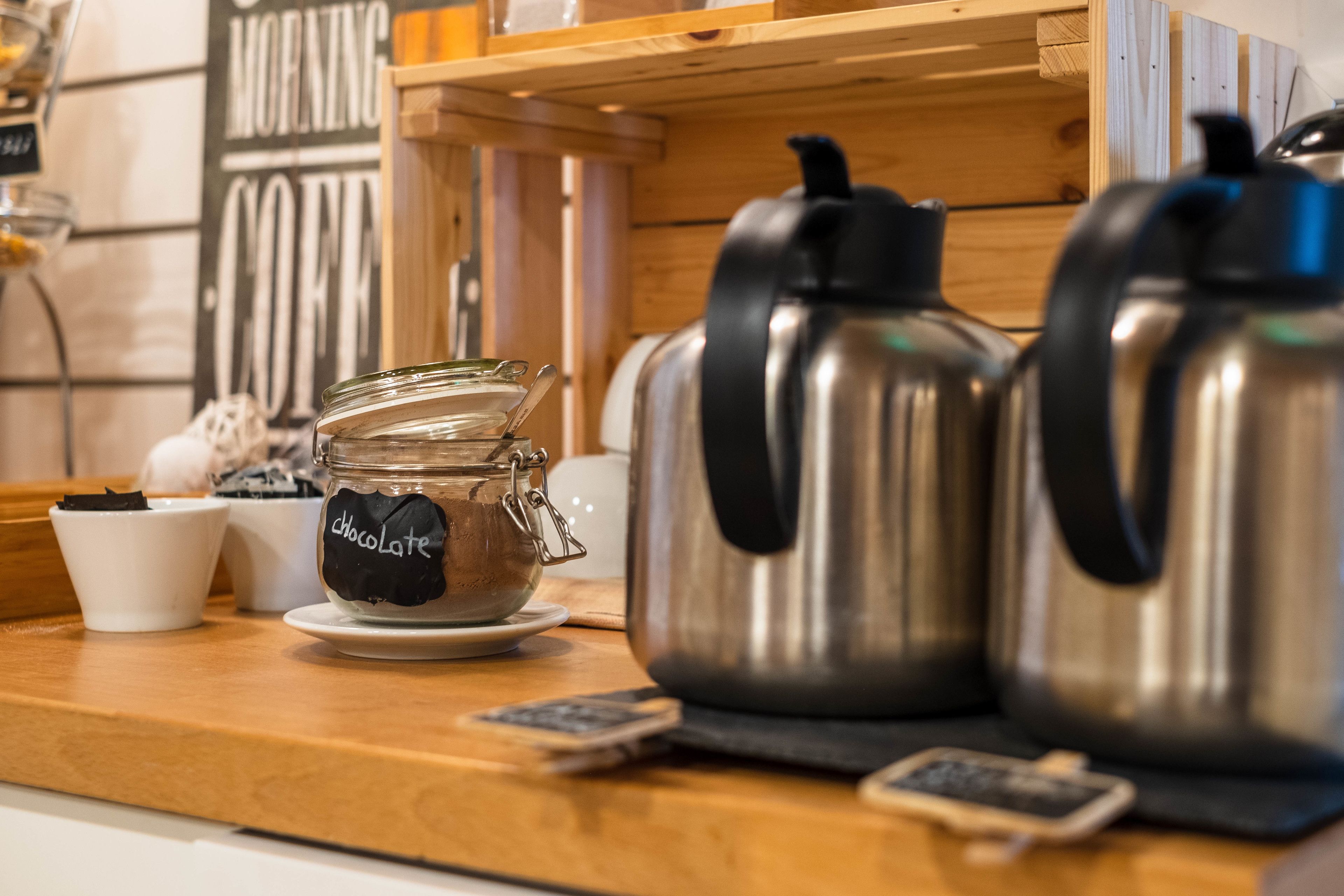 A kitchen counter with a coffee maker, a jar labeled "chocolate," and a cup.