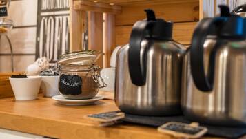 A kitchen counter with a coffee maker, a jar labeled "chocolate," and a cup.