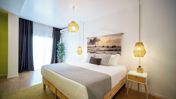 A modern bedroom with a large bed, bedside tables, and a view of the outdoors.