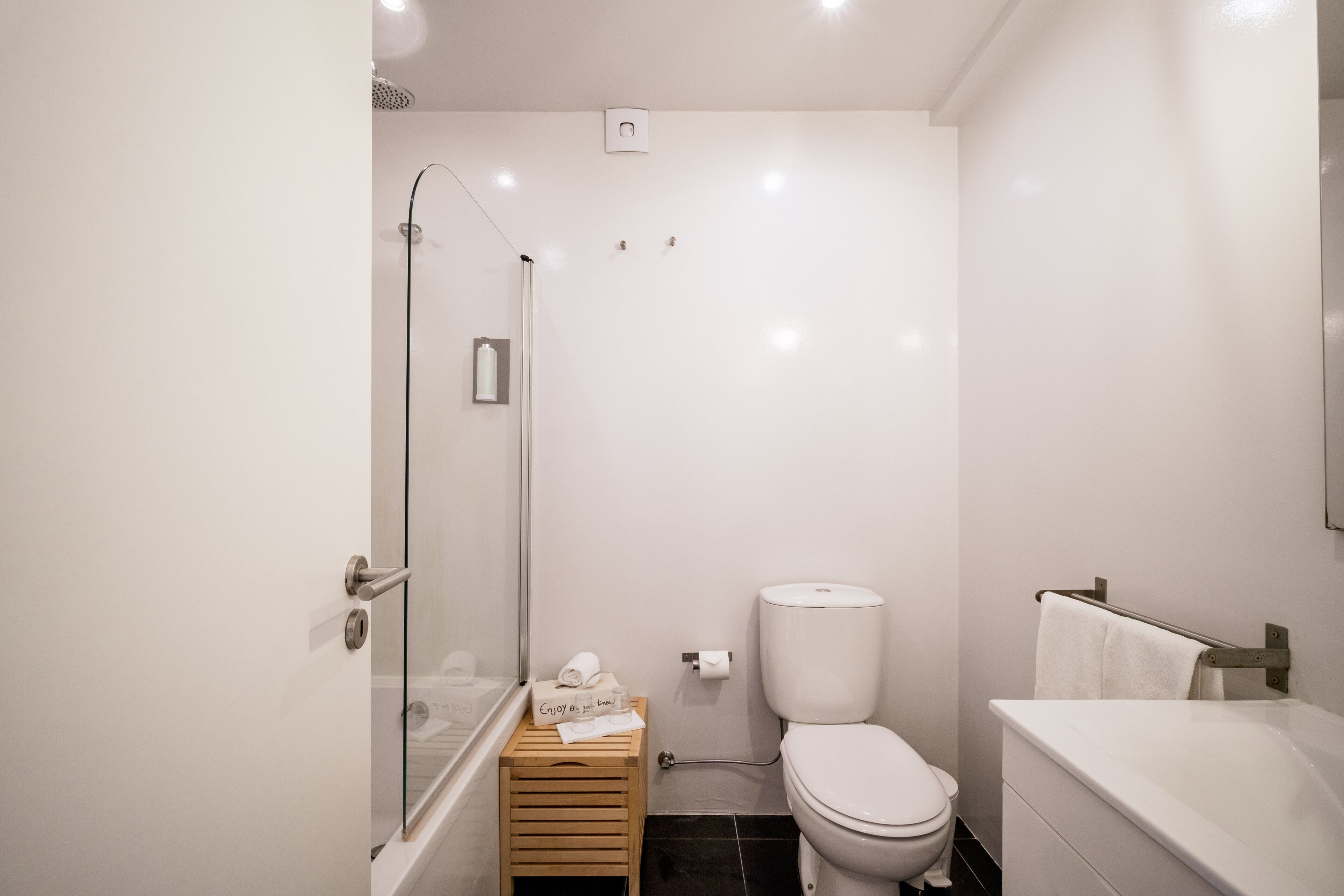A modern bathroom with a glass shower enclosure, a toilet, and a bathtub.