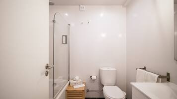 A modern bathroom with a glass shower enclosure, a toilet, and a bathtub.